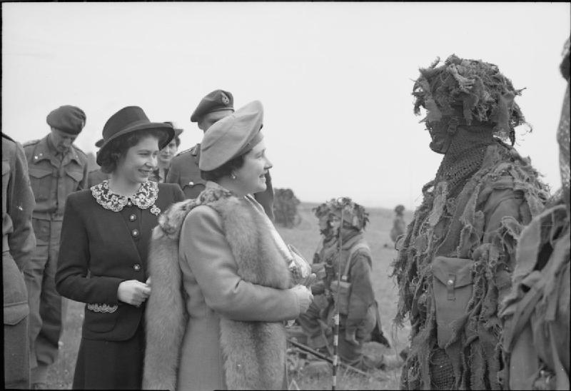 The Queen and Princess Elizabeth talk to a camouflaged sniper during a tour of Airborne forces, May 19, 1944, just weeks before D-Day.